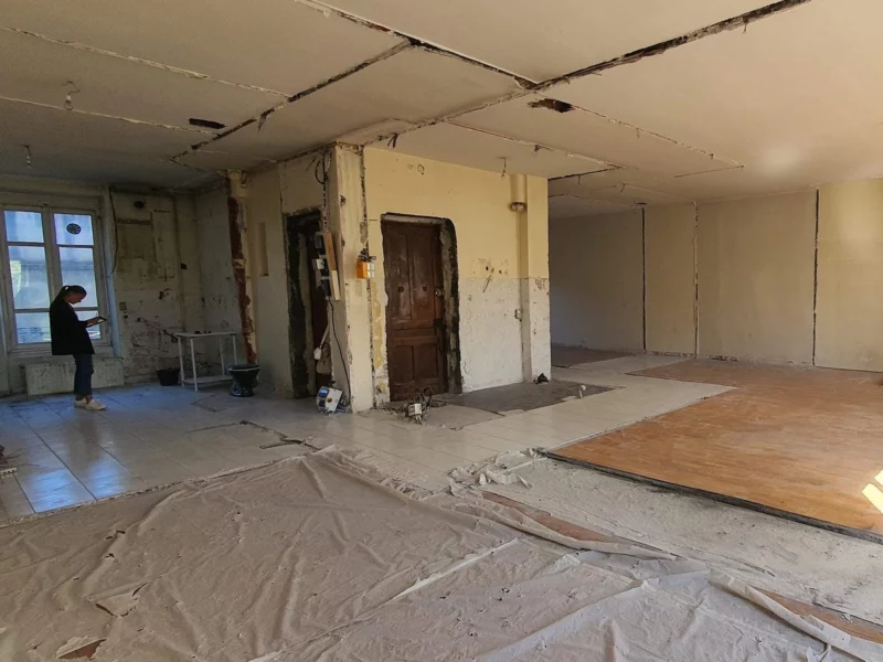 Visite d’un appartement avant travaux, pièce baignée de soleil, cloisons et sols à reprendre